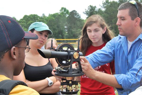 Professor working with wether equipment outside with students.